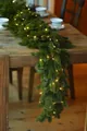 Macro shot of artificial pine needle garland featuring warm white LED fairy lights on wood - Style A 180cm With Enhanced Security Features Does Not Include Lighting.