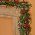 Ghirlanda natalizia artificiale con bacche rosse e pigne su un camino di legno - Foglia di Moneta Bacca Rossa - Con Luce