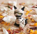 Nahaufnahme einer schwarzen Mumienkatze mit gelben Augen auf getrockneten Blumen - Mumien Stil