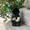 Close-up of Grim Reaper figurine holding a cat and coffee cup on a stone surface - Cat-Holding Grim Reaper