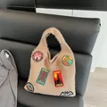 Khaki knitted tote bag with colorful cryptid creature embroidered patches on leather sofa - Khaki