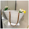 Detalle de bolso tote tejido con asas de cuero marrón y remaches metálicos de refuerzo - Blanco