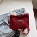 Borsa a tracolla minimalista in tela rossa con toppa in pelle su sfondo lifestyle moderno - Rosso