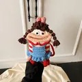 Detailed close-up of a handmade crochet doll crossbody bag with blue and red dress - Red