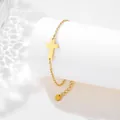 Detailed macro view of a gold cross pendant bracelet with heart charm on a white pedestal - Sideways Cross Style (SLJ68)