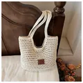 Close-up of cream woven crochet tote bag with brown leather logo patch on white bedding - Large / Cream (With Label)