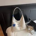 Minimalist cream canvas hobo tote bag with black lettering and blue charm detail - White