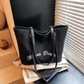 Dettaglio della borsa tote in tela nera con stampa bianca e spalline in pelle - Nero