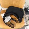 Große schwarze Messenger-Tasche aus gewaschenem Canvas in Halbmondform auf einem Stuhl - Schwarz