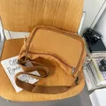 Braune Messenger-Bag aus gewaschenem Canvas für Studenten mit verstellbarem Gurt auf Holzstuhl - Braun