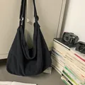 Detalle de un gran bolso bandolera de lona negra colgado en un ambiente vintage sobrio - Negro