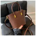 Detalle del bolso marrón con textura de cocodrilo, herrajes dorados y doble asa - Talla única / café
