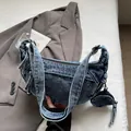 Close-up of denim shoulder bag with a round coin purse charm and tassel detail - Vintage Blue