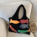 Sac hobo noir en peluche avec charms poissons colorés sur un canapé en tissu blanc - Noir