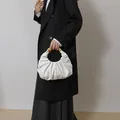 Detail of white pleated dumpling bag featuring a premium gold semi-circle metal handle - White
