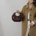 Detail of vintage pleated dark brown clutch bag featuring elegant golden metal handle - Red