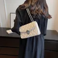 Elegant beige quilted crossbody bag with silver chain strap shown on shoulder - White