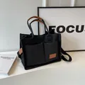 Grande borsa tote in tela nera con finiture in pelle marrone e doppie tasche frontali donna - Nero