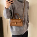 Vintage brown leather handbag with bronze twist lock and adjustable crossbody strap - Brown