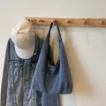 Klassische blaue Denim-Einkaufstasche mit minimalistischen Nähten am Holzhaken - Hellblau