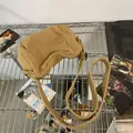 Detailopname van kaki canvas schoudertas met brede band en rits op een metalen rek - Khaki