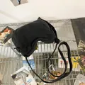 Bovenaanzicht van een zwarte canvas crossbodytas met verstelbare riem op een creatieve achtergrond - Zwart