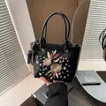 Elegant black leather bucket bag featuring pink floral embroidery and dual handles - Black