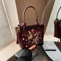 Elegant burgundy bucket bag with intricate floral embroidery and top handle design - Burgundy