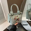 Light blue bucket bag featuring floral embroidery and knotted handles for spring fashion - Blue