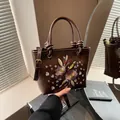 Dark brown leather bucket bag with floral embroidery and adjustable strap - Brown