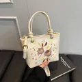 Sac seau brodé blanc crème avec motifs floraux élégants et détails dorés chics - Blanc Cassé