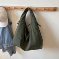 Olive green hobo bag with drawstring side pockets shown in a home setting - Green