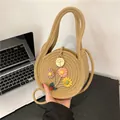 Ronde geweven strooien handtas met kleurrijke bloemen en houten bedeltje als detail - Khaki