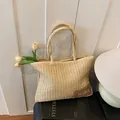 Dettaglio della trama della borsa tote in paglia con toppa in pelle su sfondo di legno bianco - Beige