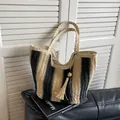 Stroh-Stofftasche mit schwarz-beigen Streifen und dekorativem Quastenanhänger - Schwarz