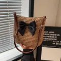Handmade straw woven shoulder bag featuring a large black ribbon bow and leather strap - Solid Bow Decor Khaki