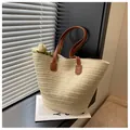 Close-up of woven straw tote bag texture with premium brown leather handles - Off White