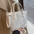 Beige bucket bag with floral embroidery, leather trim, and adjustable shoulder strap - White