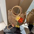 Detail of a handmade half-moon straw woven bag featuring floral charms and round handles - Khaki Orange Flower