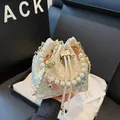 Beigefarbene Beuteltasche mit Wolkenstickerei, Perlengriff und goldenem Kettenriemen - Beige