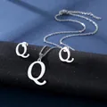Nahaufnahme von silbernem Edelstahl Q-Buchstaben Halsketten und Ohrring Set auf Ständer - Buchstabe Q / Silber