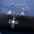 Detail of silver bow pendant necklace and matching stud earrings on black display - Bowknot Style (TZ-86)
