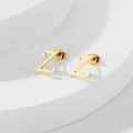 Dettaglio di un orecchino a lobo dorato lettera Z su un supporto geometrico bianco - Lettera Z / Oro