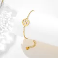 Detail of gold stainless steel bracelet with clover-shaped heart cutout pendant on a stand - Heart Clover Style (SLJ75)