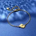 Dettaglio di un bracciale dorato con ciondolo a piedini su sfondo di seta blu satinata - Stile Piedini di Neonato (XLJ104)