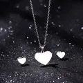 Polished stainless steel heart necklace and stud earrings set on a sparkly black background - Smooth Heart Style (TZ-443)