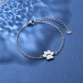 Minimalist stainless steel bracelet featuring a hollow paw print charm on a blue backdrop - Paw Print Style (XLY40 Steel)
