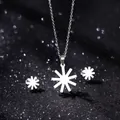 Macro view of silver starburst pendant necklace and stud earrings set on black background - Radiant Star Style (TZ-419)