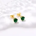 Gros plan de boucles d'oreilles couronne dorées avec zircons verts brillants - Vert foncé