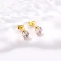 Détail de boucles d'oreilles couronne dorées avec des pierres d'oxyde de zirconium - Blanc
